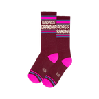 Pair of burgundy crew socks with "BADASS GRANDMA" in white, hot pink toes, and horizontal pink and blue stripes on the cuff.