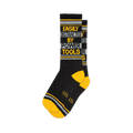 Black crew socks with "EASILY DISTRACTED BY POWER TOOLS" in yellow and gray text, featuring yellow toes and cuff stripes.