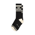 Black "Shit Happens" crew socks with white text and stripes, ribbed cuff, and contrast cream heel and toe.