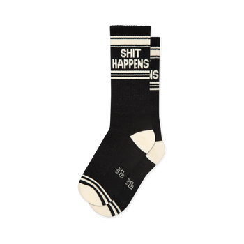 Black "Shit Happens" crew socks with white text and stripes, ribbed cuff, and contrast cream heel and toe.