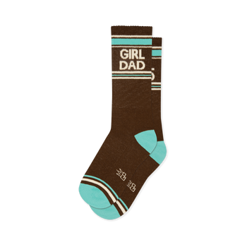 Brown crew socks with 'GIRL DAD' in white lettering, bordered by teal and off-white stripes. Features teal toe and heel, plus small white crown shapes.
