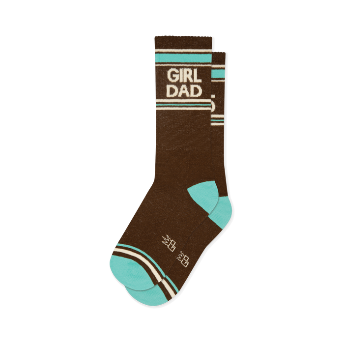 Brown crew socks with 'GIRL DAD' in white lettering, bordered by teal and off-white stripes. Features teal toe and heel, plus small white crown shapes. }}