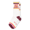 White athletic crew socks with HOT CHEF in bold orange letters, featuring retro stripes in maroon, yellow, pink, and white.
