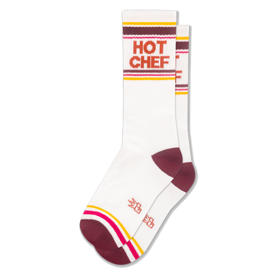 White athletic crew socks with HOT CHEF in bold orange letters, featuring retro stripes in maroon, yellow, pink, and white.