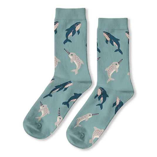 Light blue crew socks featuring a scattered pattern of dark blue whales and grey spotted narwhals with striped tusks.