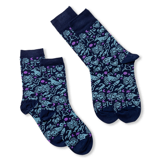Two pairs of dark blue socks with light blue zodiac signs and purple stars, laid flat against a black background.