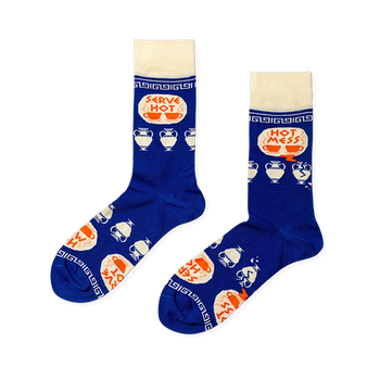 Pair of royal blue crew socks with cream cuffs, heels, toes. Features 'Serve Hot' and 'Hot Mess' text with cups and broken Greek vases.