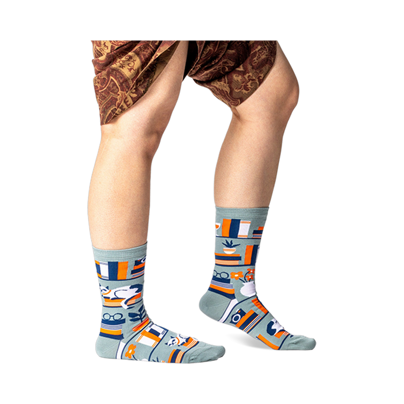 Person standing wearing sage green bookshelf crew socks, showing the full pattern on both feet and lower legs.