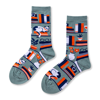 Pair of crew socks in sage green with a bookshelf pattern. Design includes books, a white cat, plants, and reading glasses.