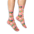 [lf] Someone wearing dusty pink socks with a colorful butterfly and caterpillar pattern against a solid black background.