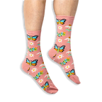 [lf] Someone wearing dusty pink socks with a colorful butterfly and caterpillar pattern against a solid black background.