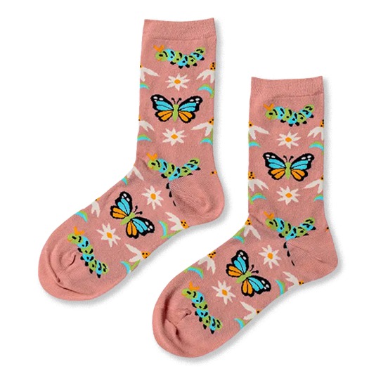 A pair of dusty pink crew socks showing a pattern of blue butterflies, green caterpillars, white daisies, and blue stems.
