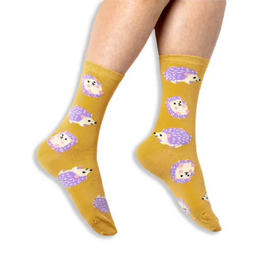 [lf] Person wearing mustard yellow crew socks with a pattern of purple and cream hedgehogs against a black background.