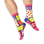 [lf] A person wearing bright patchwork socks featuring strawberries, tulips, polka dots and stripes on a black background.