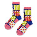 Crew socks with a colorful patchwork design of strawberries, tulips, polka dots and stripes separated by wavy blue borders.