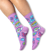 [lf] A person wearing purple crew socks featuring a retro charm pattern with teddy bears and keyboards on a black background.
