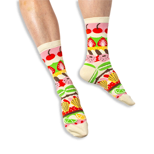 [lf] A person wearing cream crew socks featuring horizontal colorful stripes of pastries, cherries, and citrus slices.