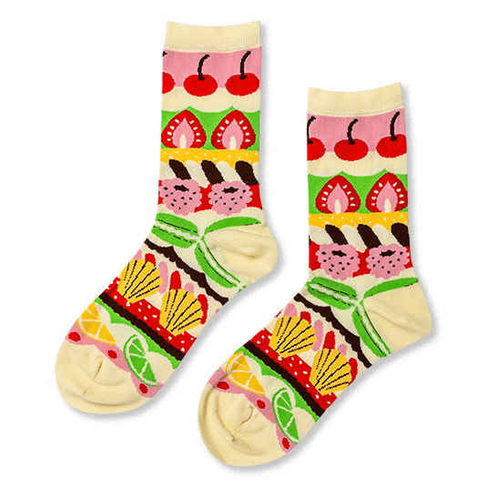 Cream crew socks with colorful horizontal bands showing patisserie items like cherries, strawberries, madeleines, and citrus.