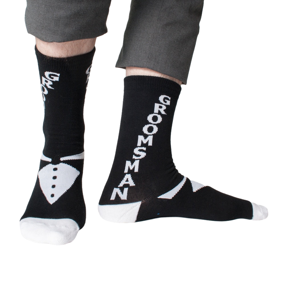 Lifestyle shot: Man modeling black 'Groomsman' socks with gray pants.  Shows the full sock design.