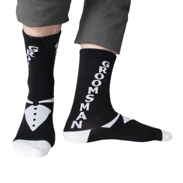 Lifestyle shot: Man modeling black 'Groomsman' socks with gray pants.  Shows the full sock design.