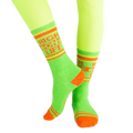 Lifestyle shot of 'High On Life' socks on a model's legs; vibrant lime green socks with orange details against a light background. [lf]