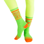 Lifestyle shot of 'High On Life' socks on a model's legs; vibrant lime green socks with orange details against a light background. [lf]