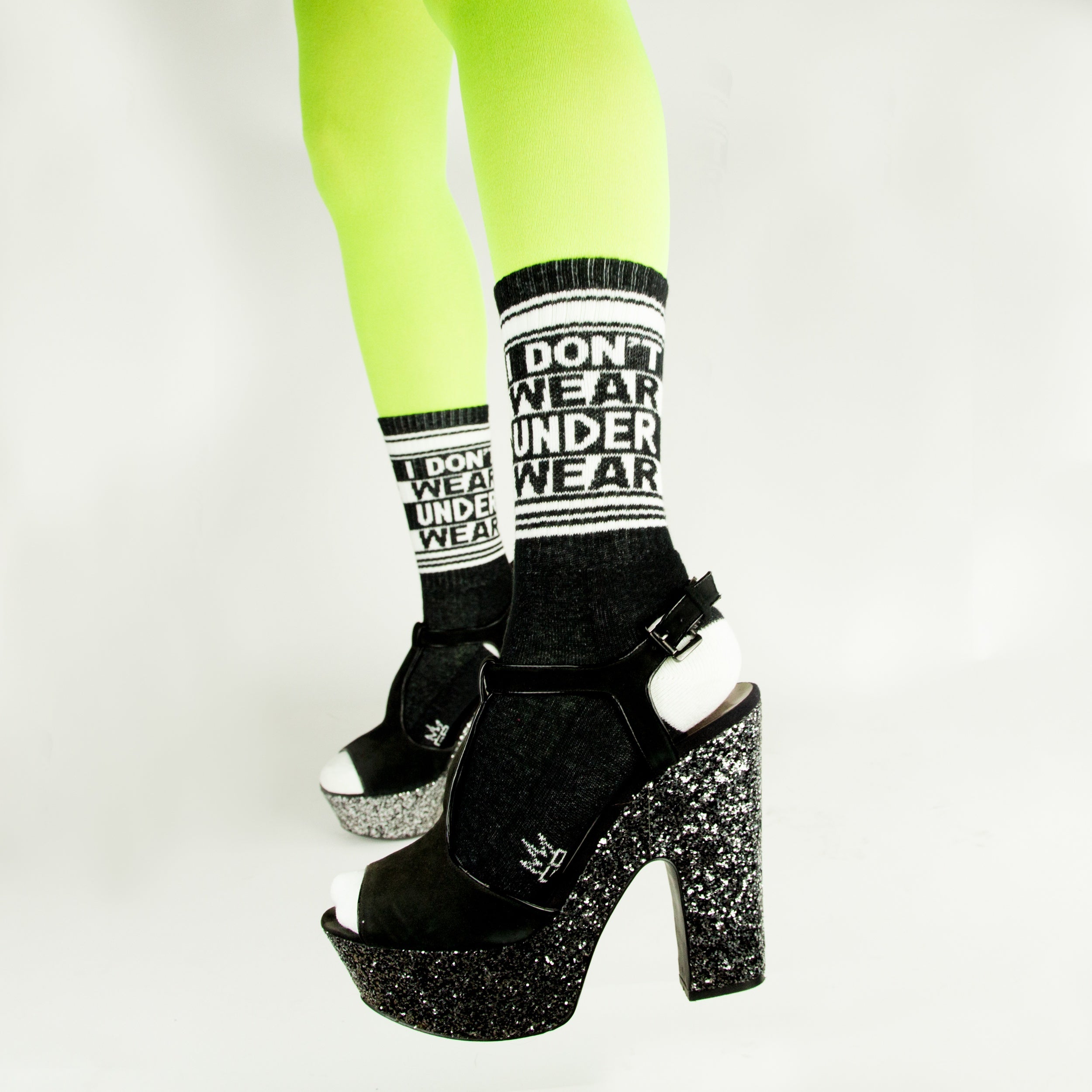 Lifestyle shot: Model wearing neon green tights and black platform shoes with the 'I Don't Wear Underwear' socks.