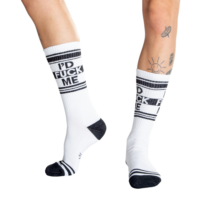 Close-up shot of a person's legs wearing white 'I'd Fuck Me' socks and silver platform shoes.