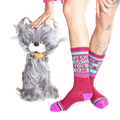Lifestyle photo showing a model wearing the 'My Cat Says You're Dumb' socks with a fluffy gray cat toy.