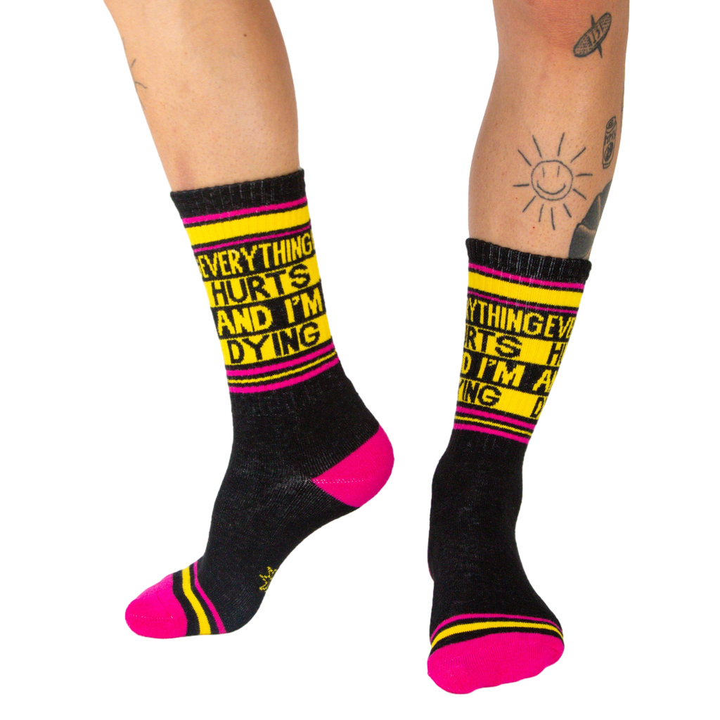 Lifestyle photo showing a person wearing the black 'Everything Hurts And I'm Dying' crew socks.