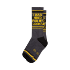 Crew socks in dark gray, black, and yellow.  The socks feature a bold graphic print that says 'I WAS HIRED FOR MY LOOKS'.