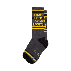 Crew socks in dark gray, black, and yellow.  The socks feature a bold graphic print that says 'I WAS HIRED FOR MY LOOKS'.