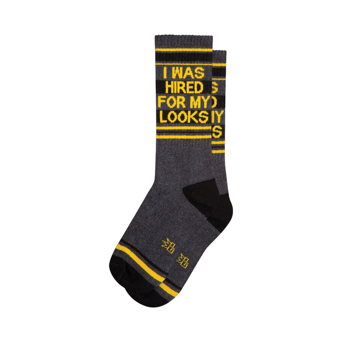 Crew socks in dark gray, black, and yellow.  The socks feature a bold graphic print that says 'I WAS HIRED FOR MY LOOKS'.
