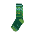 Pair of crew socks in various shades of green. The socks feature a repeating 'Plants' pattern and thin stripes at the top and bottom.