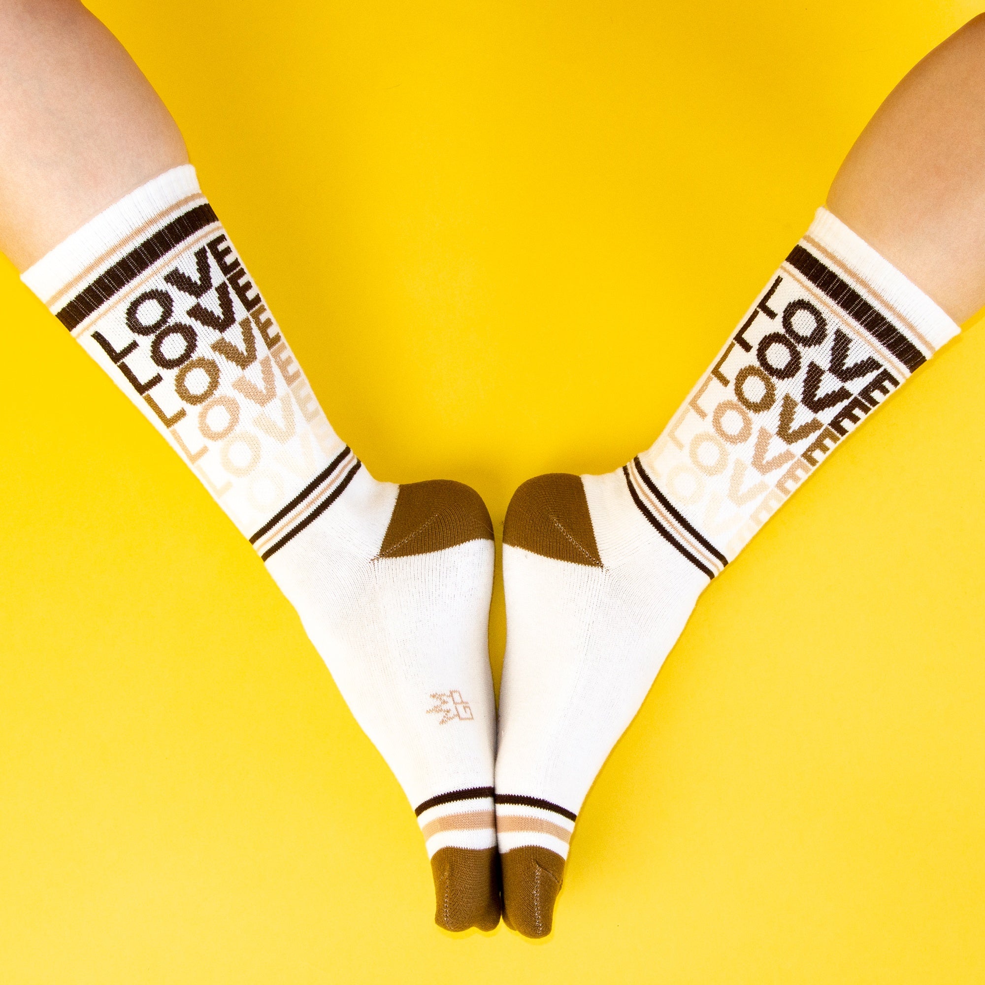 Close-up lifestyle shot of model wearing rainbow 'Love' socks. [lf]