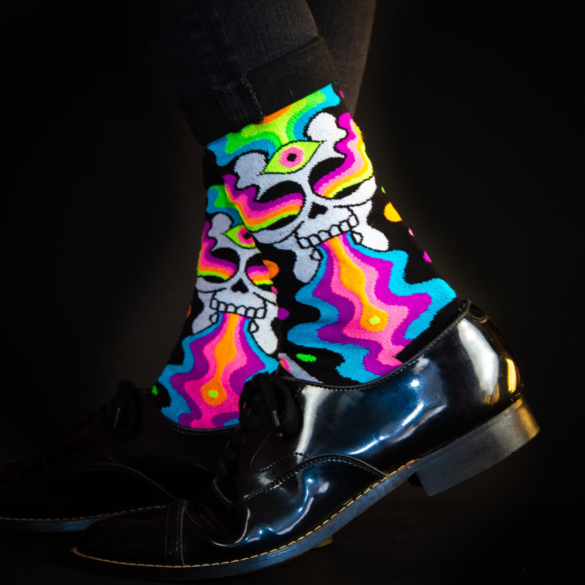 Lifestyle shot:  Model wearing Eye of the Doomed socks with black shoes, showcasing the vibrant colors against dark clothing. [lf]