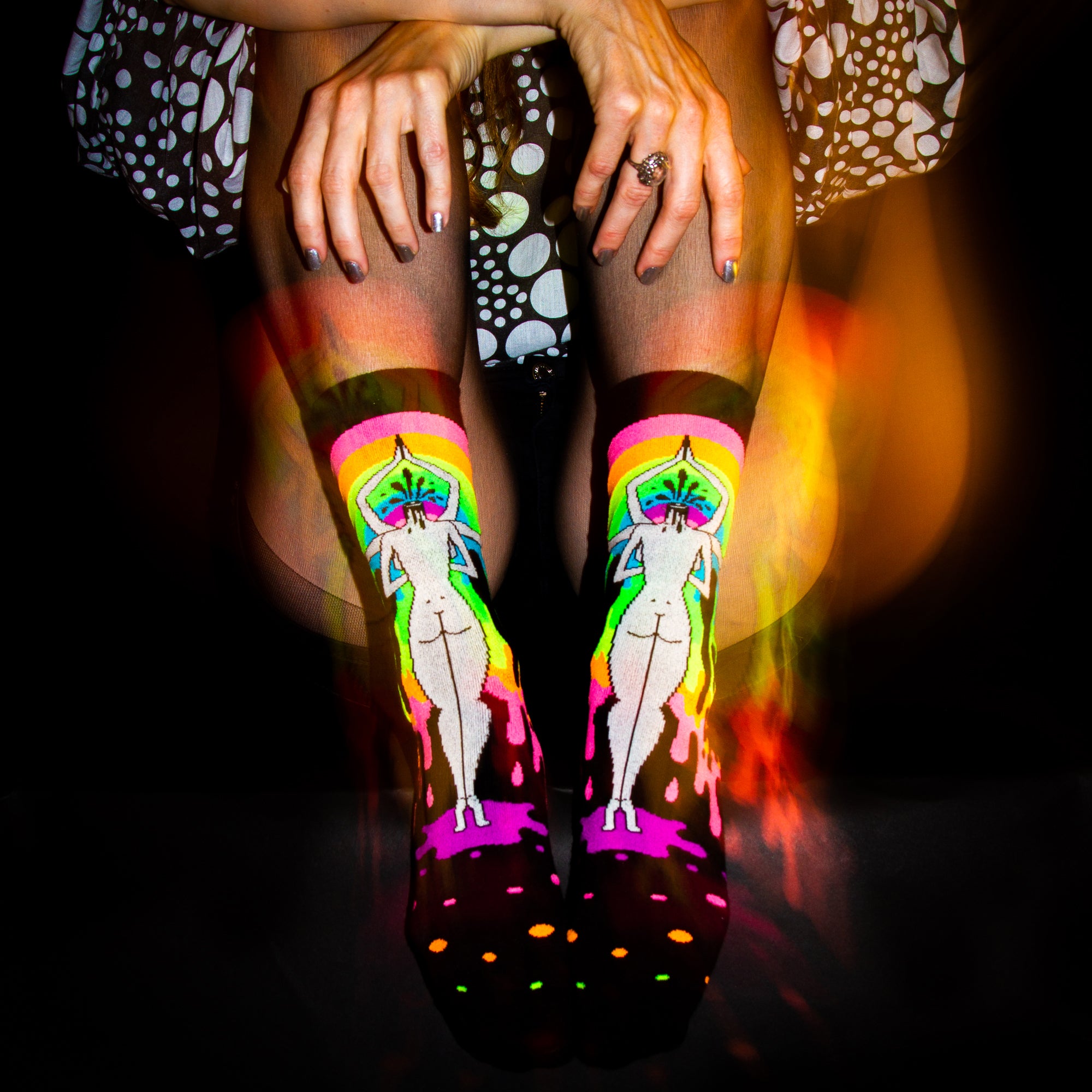 Lifestyle shot: 'Derriere of Doom' socks on a model's legs, seated; warm lighting. [lf]