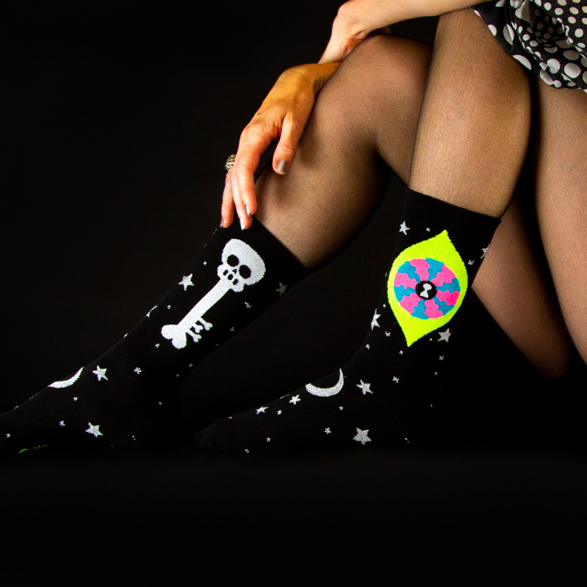 Lifestyle shot: A woman's legs in black tights and Oliver's Eye socks are shown from the knees down. [lf]