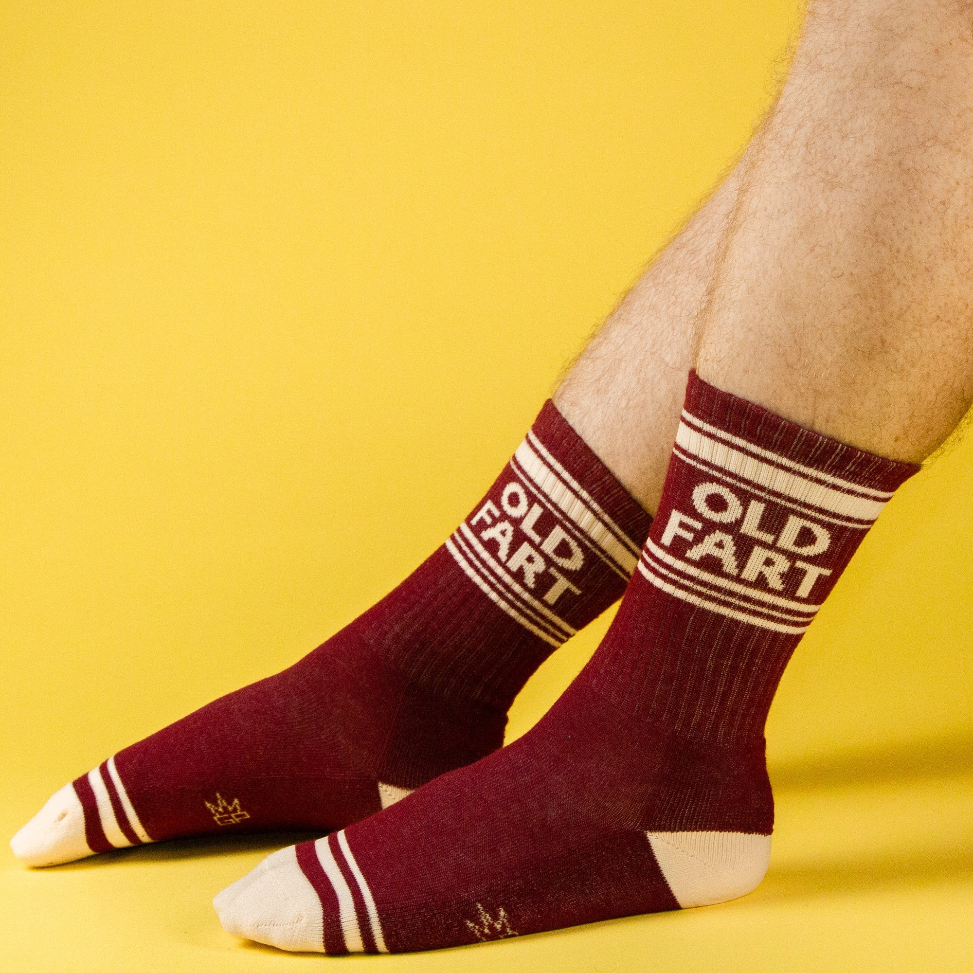 Lifestyle shot of hairy male legs wearing the 'Old Fart' socks against a yellow background. [lf]