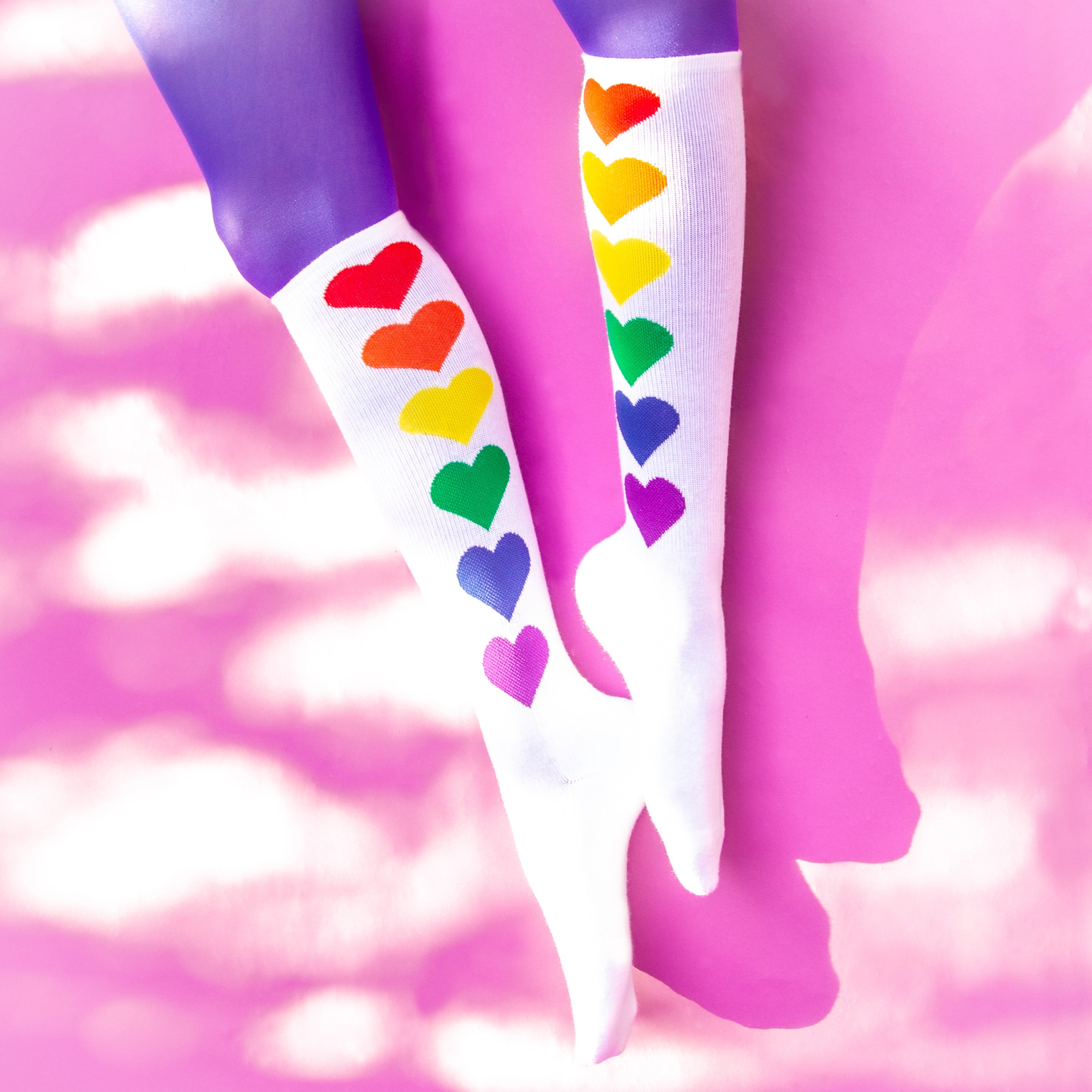 Flatlay: Pair of Rainbow Hearts socks on a pink background. [lf]