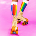 Close-up shot of legs in rainbow socks and roller skates, pink background. [lf]