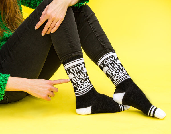 [lf] Close-up shot: A person points to the 'I Give The Best Blow Jobs' socks worn on their leg.