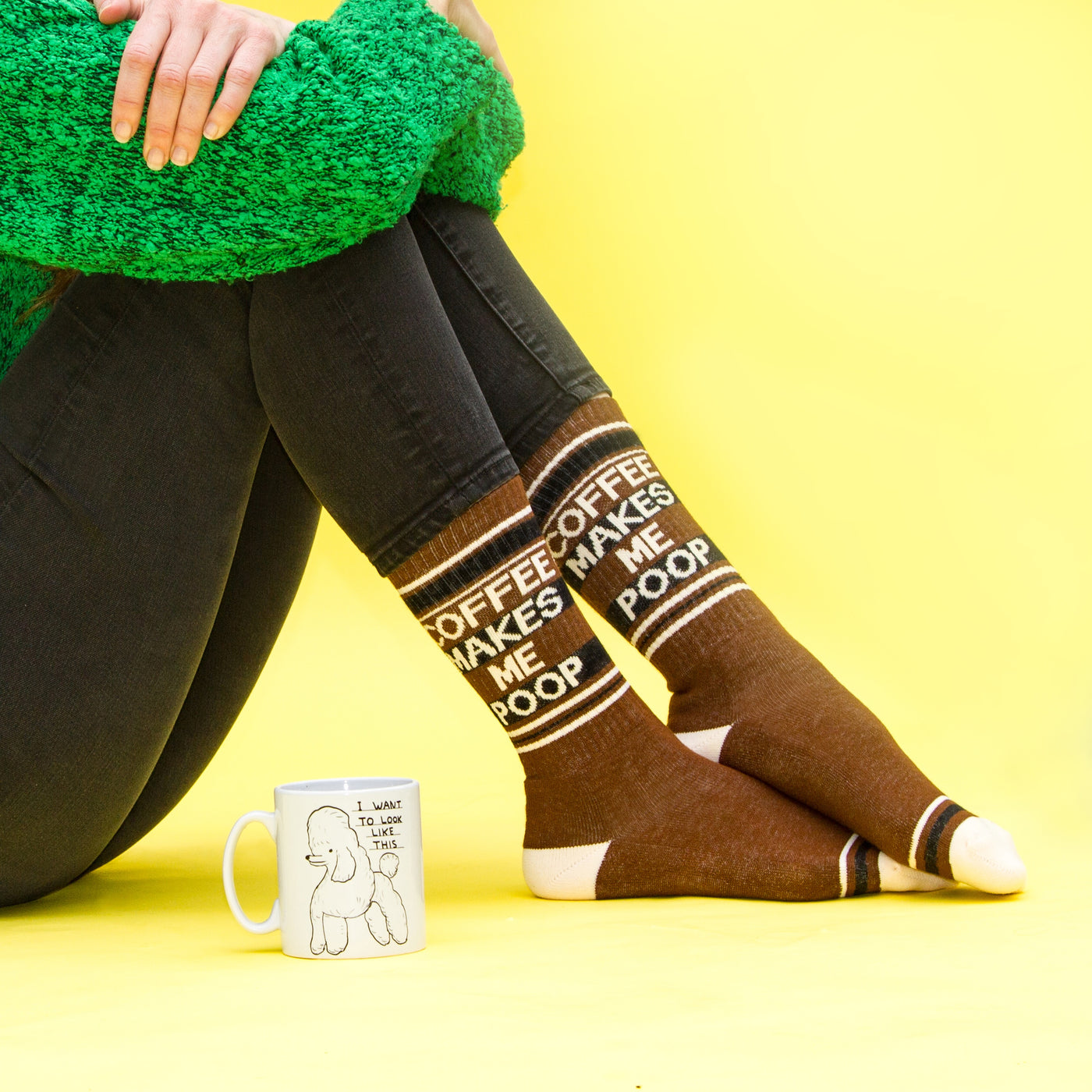 Lifestyle photo showing a person wearing the 'Coffee Makes Me Poop' socks with a coffee mug. [lf]