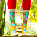 Close-up shot of a pair of Lazy Lizard socks on a wooden surface, highlighting the sock's design details. [lf]