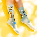 Flat lay of Cat & Clouds socks on a yellow background. [lf]