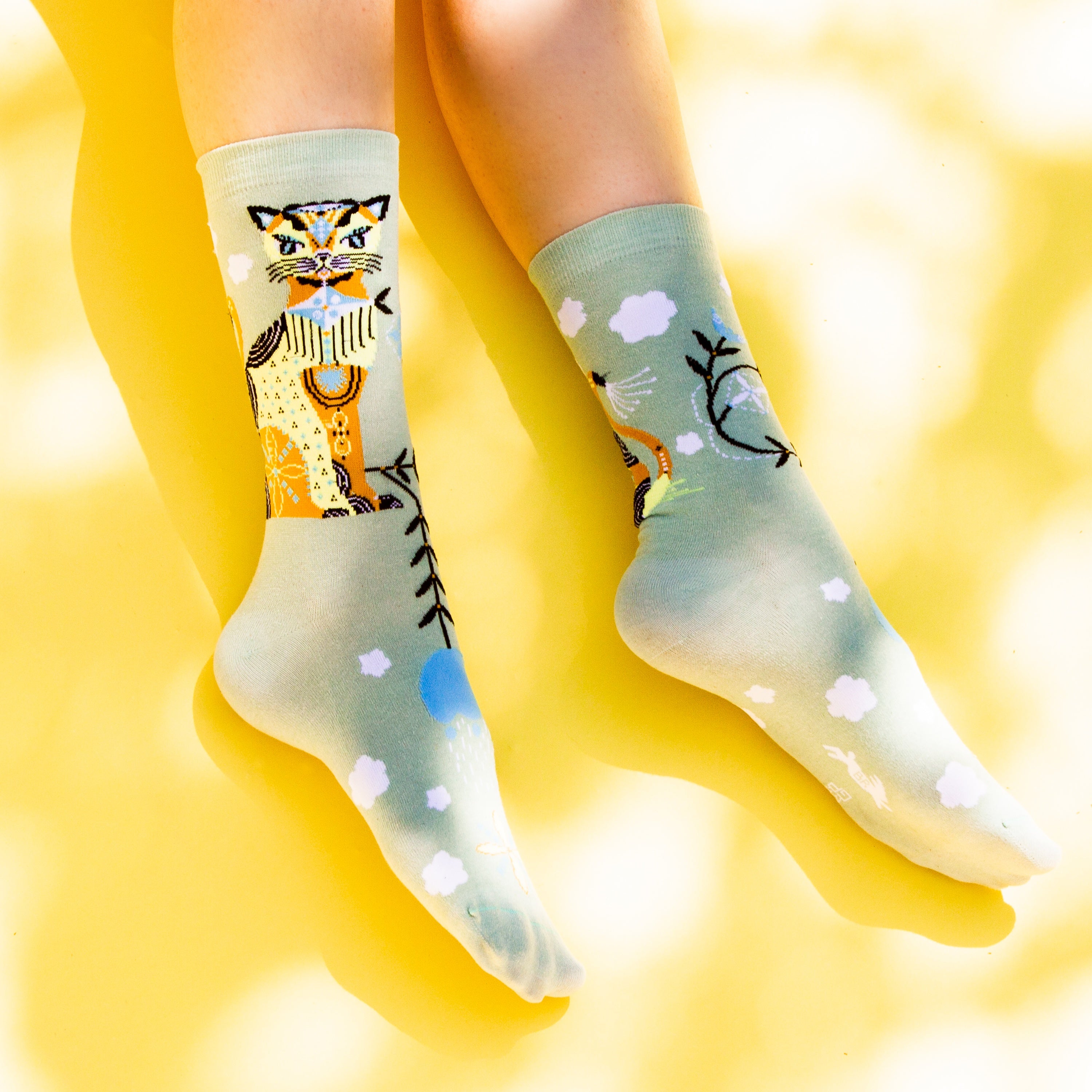 Flat lay of Cat & Clouds socks on a yellow background. [lf]