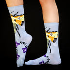 Studio shot of a pair of Bee & Flowers socks against a black background. [lf]