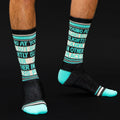 Lifestyle shot of a person's legs wearing the 'Young at Heart' socks against a dark background. [lf]