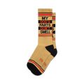 A pair of tan crew socks with black and orange stripes and the text 'MY DOG'S FARTS DON'T SMELL' in black.