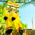 Close-up of yellow 'Someone in California Loves Me' socks hanging on a clothesline outdoors. [lf]